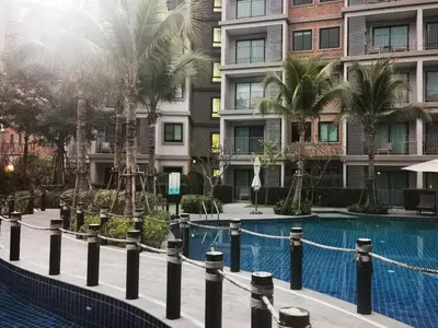 a swimming pool with palm trees and buildings at 2 Bedrooms Suite Pool Access@The Title Residencies Naiyang in Nai Yang Beach