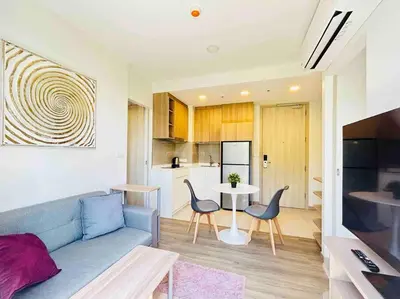 a living room with a blue couch and a table at Sky park 2 BR lake view in Bang Tao Beach