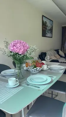 a table with plates and a vase of pink flowers at Townhouse in the Wonderland in Bang Tao Beach