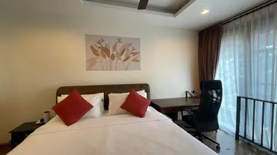 a bedroom with a bed with red pillows and a desk at Townhouse in the Wonderland in Bang Tao Beach