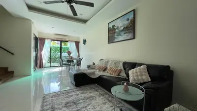 a living room with a black couch and a table at Townhouse in the Wonderland in Bang Tao Beach