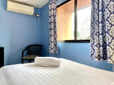 a blue bedroom with a bed and a chair and a window at Minotel Patong in Patong Beach