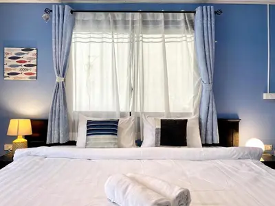 a bedroom with a large bed with blue walls and a window at Minotel Patong in Patong Beach
