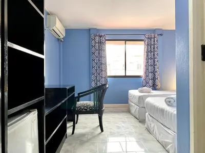 a blue room with a desk and a bed and a window at Minotel Patong in Patong Beach