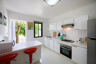 a kitchen with white cabinets and red stools in it at Modern & fun pool villa at Kamala regent in Kamala Beach