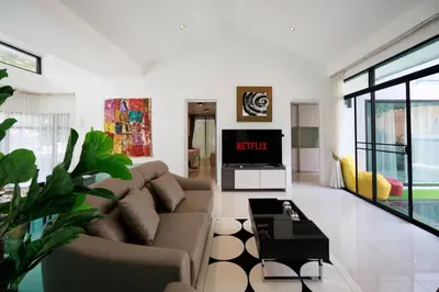 a living room with a couch and a tv at Modern & fun pool villa at Kamala regent in Kamala Beach