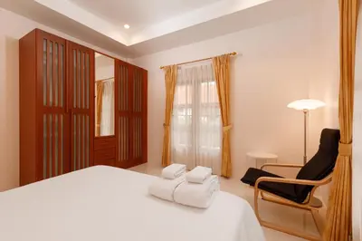 a bedroom with a white bed and a chair at Villa with pool, garden and terrace - Kamala #123 in Phuket Town