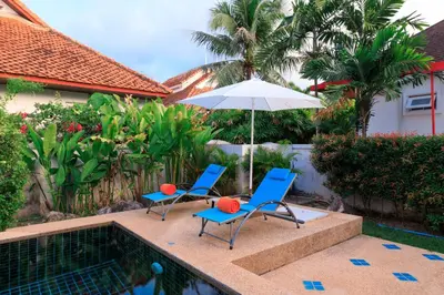 two chairs and an umbrella next to a swimming pool at Villa with pool, garden and terrace - Kamala #123 in Phuket Town