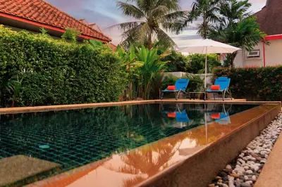 a swimming pool with two chairs and an umbrella at Villa with pool, garden and terrace - Kamala #123 in Phuket Town