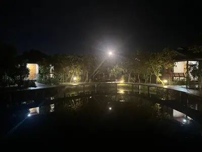 a nightime view of a bridge over a pond at The Beatles Lagoon in Ban Na Bon