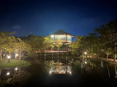 a building on a dock in the middle of a river at night at The Beatles Lagoon in Ban Na Bon