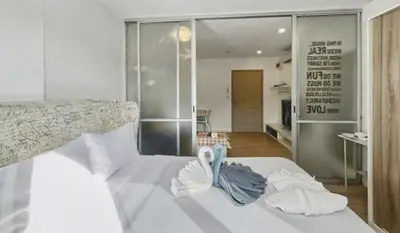 a bedroom with a white bed with towels on it at Dcondo Kathu - Top Floor 1 Bdr Condo with shared Pool in Kathu