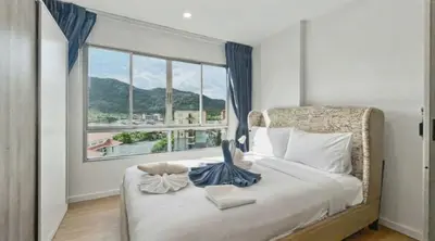 a bedroom with a bed and a large window at Dcondo Kathu - Top Floor 1 Bdr Condo with shared Pool in Kathu