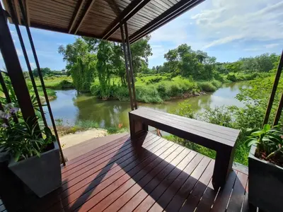a bench sitting on a deck next to a river at Baan Ati Resort & Spa in Ban Na Tai