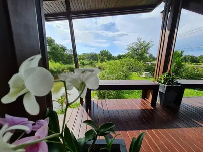 a view from a porch with a bench and flowers at Baan Ati Resort & Spa in Ban Na Tai