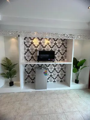 a living room with a tv and a wall at Petunya Room 2 in Ban Huai Luk (1)