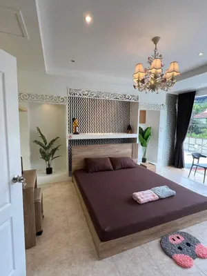 a bedroom with a large bed and a chandelier at Petunya Room 1 in Ban Huai Luk (1)