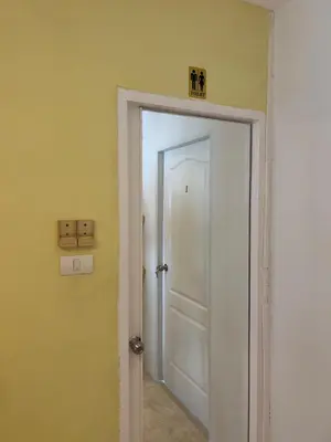 a hallway with a white door and a yellow wall at Petunya Room 1 in Ban Huai Luk (1)
