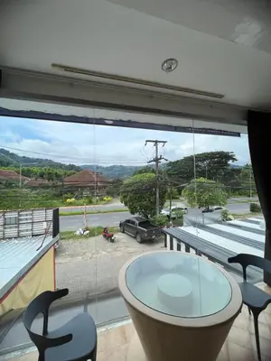 a dining room with a glass table and a large window at Petunya Room 1 in Ban Huai Luk (1)