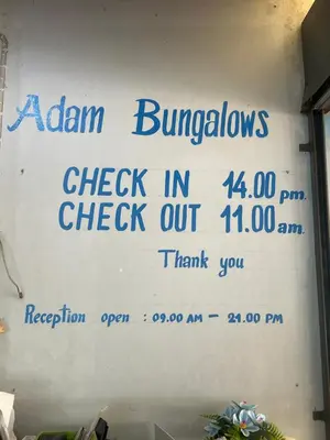 a sign on a wall that says alarminators check in check out at Adam Bungalows in Ao Nang Beach