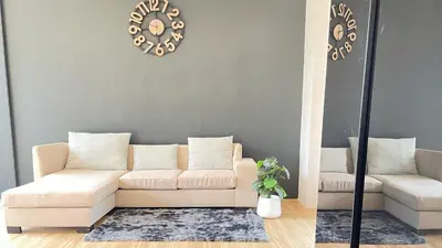 a living room with a couch and a clock on the wall at Spacious Private Villa Modern Style near beach in Thai Muang