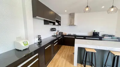 a kitchen with black cabinets and a counter top at Spacious Private Villa Modern Style near beach in Thai Muang