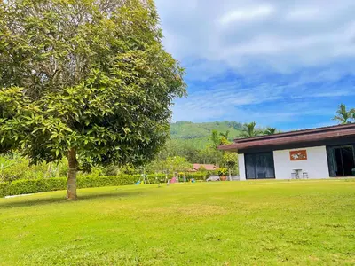 a green yard with a tree and a building at Spacious Private Villa Modern Style near beach in Thai Muang