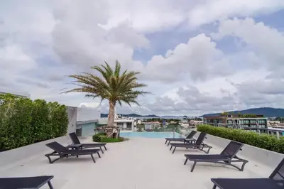 a patio with chaise lounge chairs and a palm tree at The Tower Condo Phase3 in Ban Klang