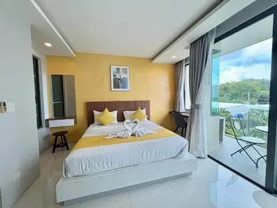 a bedroom with a large bed and a balcony at 1 Bedroom Rawai Walk to beach in Rawai Beach