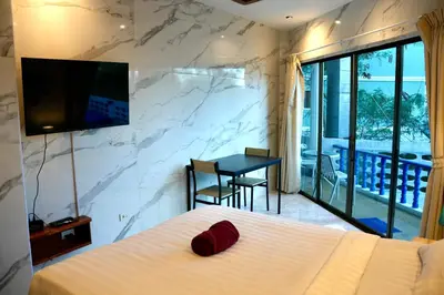 a bedroom with a bed and a table and a television at The Club Inn - Kamala Beach in Kamala Beach
