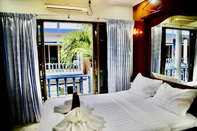 a bedroom with a bed and a large window at The Club Inn - Kamala Beach in Kamala Beach
