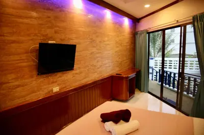 a room with a flat screen tv on a wall at The Club Inn - Kamala Beach in Kamala Beach