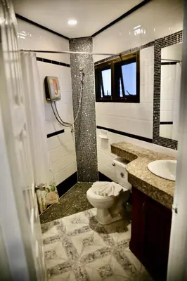 a bathroom with a shower and a toilet and a sink at The Club Inn - Kamala Beach in Kamala Beach