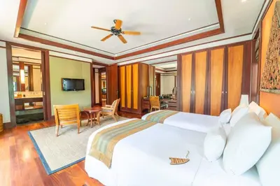 a bedroom with a large white bed with a ceiling fan at Andarada Seaview in Kamala Beach