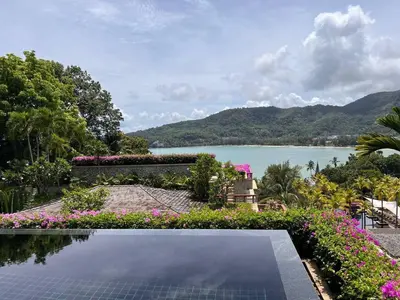 a swimming pool with flowers and a view of a lake at Andarada Seaview in Kamala Beach