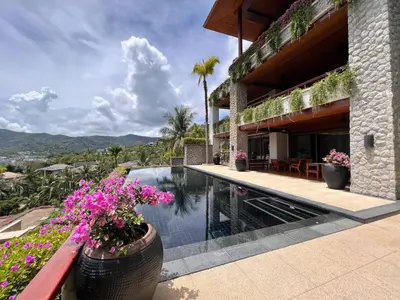 a house with a swimming pool and some flowers at Andarada Seaview in Kamala Beach