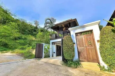 a house with a large wooden door and a balcony at Secret Balinese Escape villla Eva in Rawai Beach