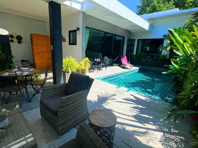 a swimming pool with chairs and a table next to a house at Intimate Oasis, 2 bedrooms Pool in Kata Beach