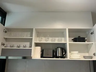 a kitchen with white shelves with cups and dishes at The Base - New Studio Great location, shared Pool in Ban Rangeng