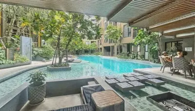 a swimming pool with two people sitting in chairs next to it at The Base - New Studio Great location, shared Pool in Ban Rangeng