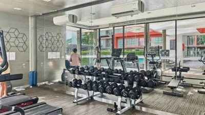 a gym with tread machines and a man in the background at The Base - New Studio Great location, shared Pool in Ban Rangeng