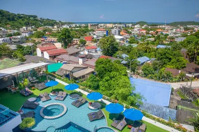 an aerial view of a resort with a pool and blue umbrellas at The Yama Hotel Phuket in Kata Beach