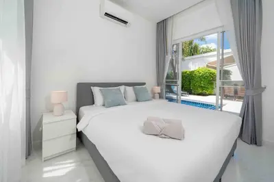a white bedroom with a large bed and a window at Brand New 3 Bedroom Pool Villa in Ban Saiyuan (1)