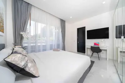 a white bedroom with a large bed and a desk at Brand New 3 Bedroom Pool Villa in Ban Saiyuan (1)