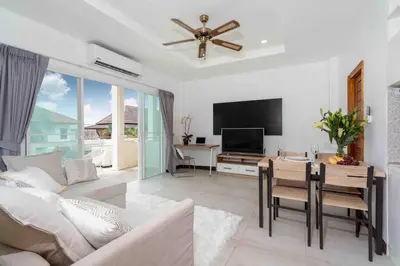 a living room with a television and a table with chairs at 1 bedroom apartment in Nai Harn in Ban Saiyuan (1)