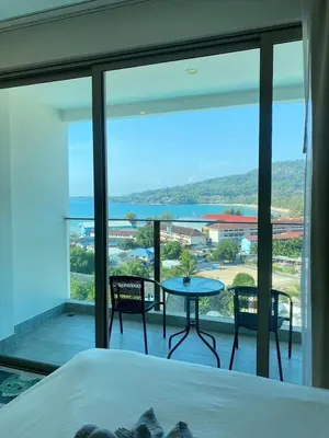 a bedroom with a bed and a view of a balcony at OCEANA HOME Phuket Kamala in Kamala Beach