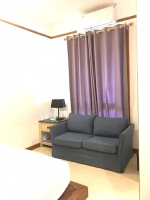 a living room with a couch and purple curtains at Plumeria Villa Thalang in Ban Pak Lak