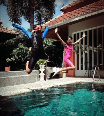 a man and a girl jumping into a swimming pool at Plumeria Villa Thalang in Ban Pak Lak