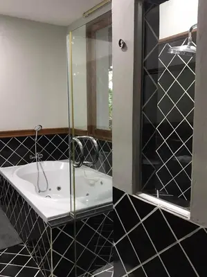 a black and white bathroom with a tub and a mirror at Plumeria Villa Thalang in Ban Pak Lak