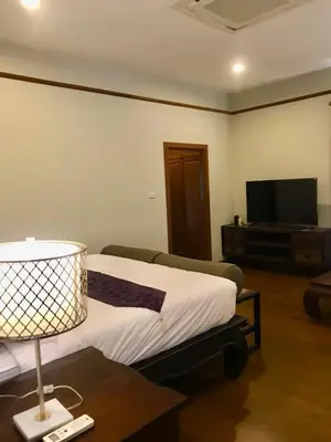 a bedroom with a bed and a table with a lamp at Plumeria Villa Thalang in Ban Pak Lak